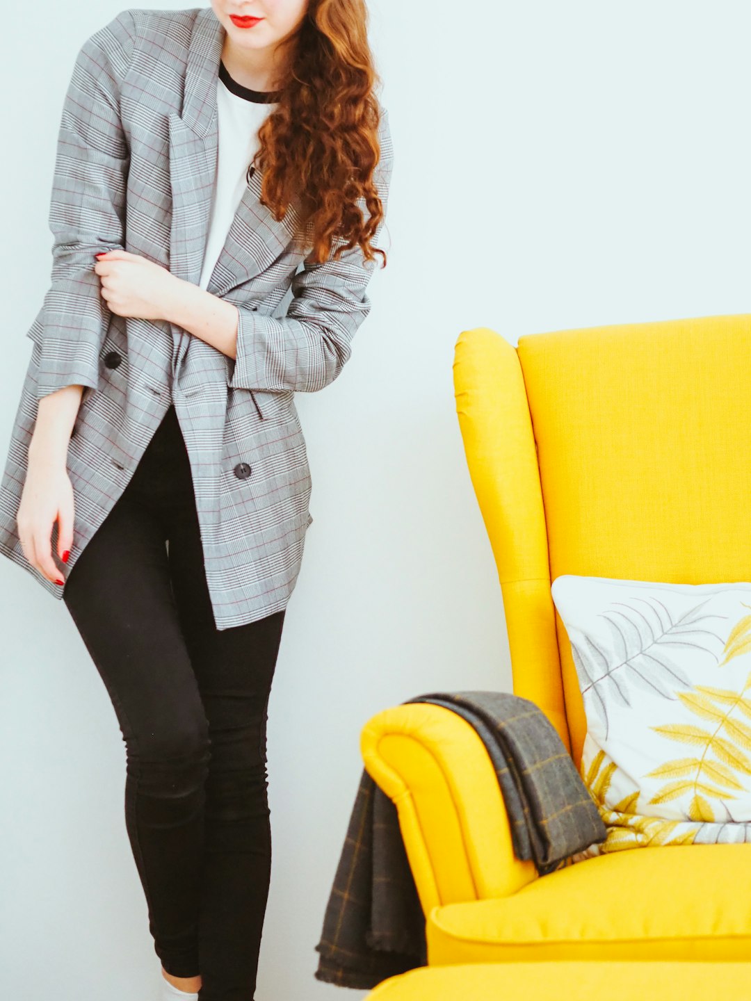 woman in gray blazer and black pants standing beside yellow sofa