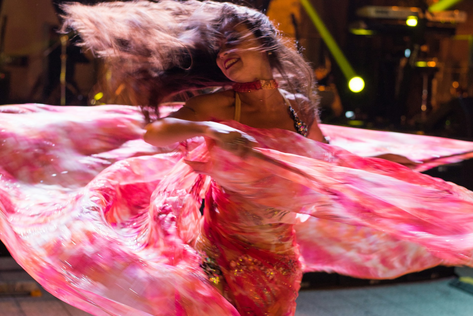 A passionate flamenco dancer captured mid-move, her flowing dress swirling with vibrant colors under stage lights.