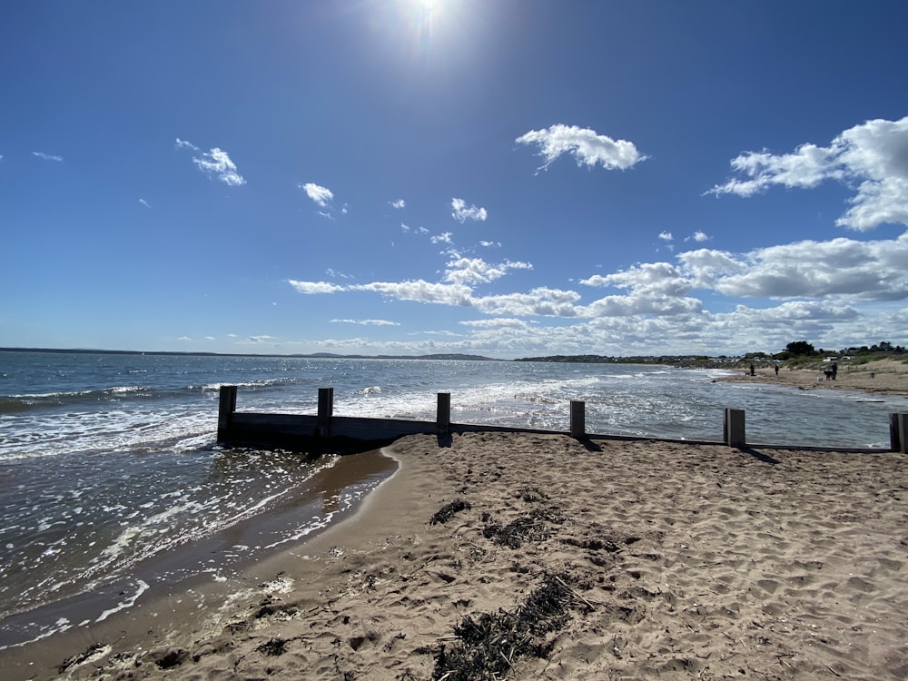 brown wooden dock on sea under blue sky during daytime