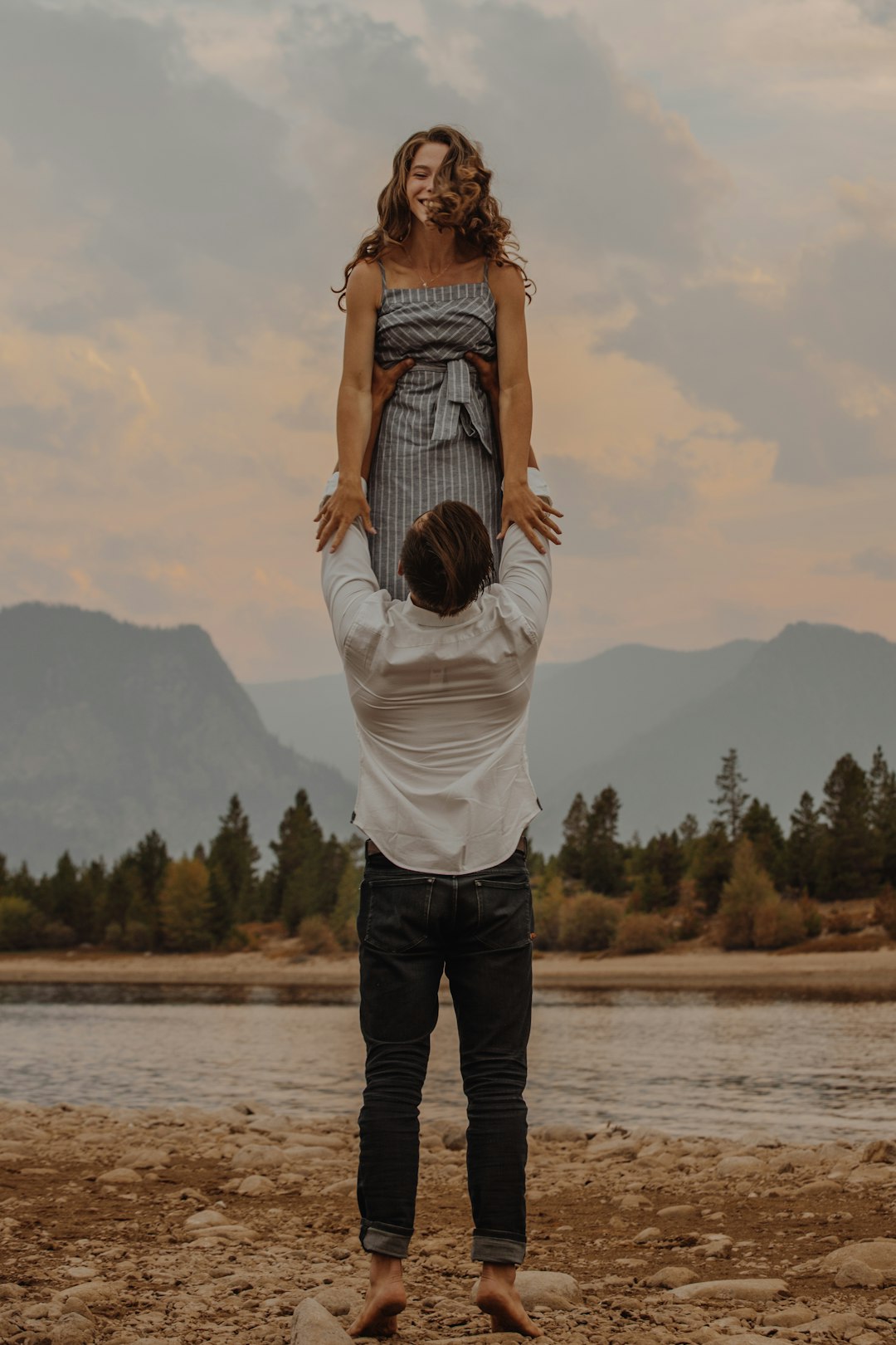 woman in white long sleeve shirt and black pants standing on brown wooden dock during daytime