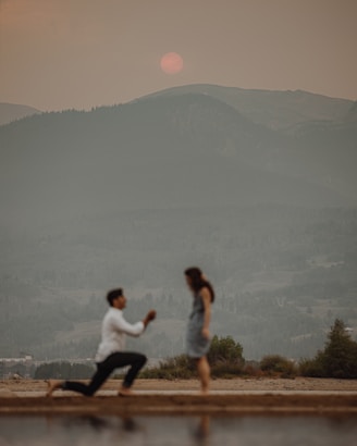 man in white shirt and black pants sitting on brown wooden bench during daytime