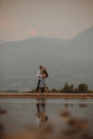 A tender moment captured at sunset by Erhai Lake, with warm light casting long shadows over the couple walking hand in hand.