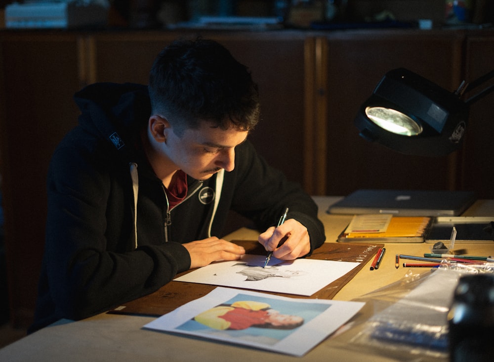 man in black jacket writing on white paper