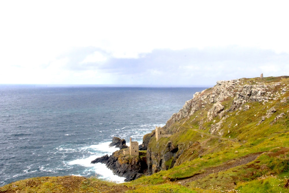 green and brown mountain beside sea under white sky during daytime