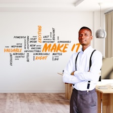 man in white dress shirt and gray pants standing beside brown wooden table