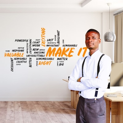 man in white dress shirt and gray pants standing beside brown wooden table