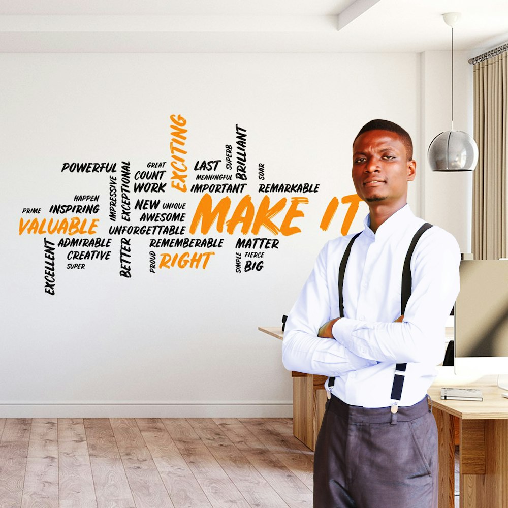 man in white dress shirt and gray pants standing beside brown wooden table