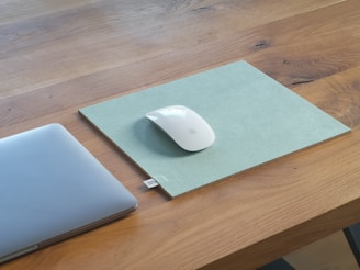 A minimalist workspace with a laptop and design sketches on a wooden table.