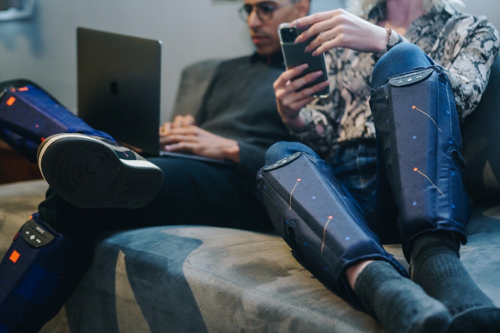 man in black shirt and blue denim jeans sitting on gray couch