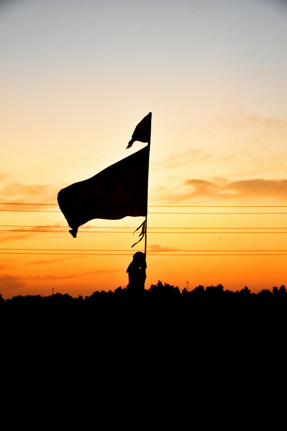 Silueta del hombre sosteniendo la bandera durante la puesta del sol