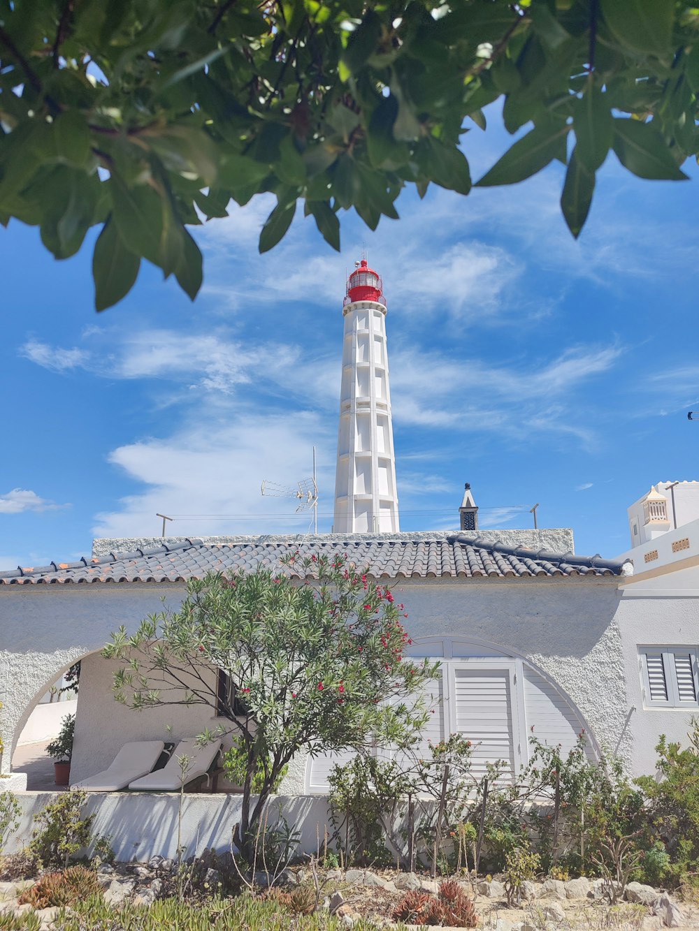 white and red lighthouse near white concrete building under blue sky during daytime