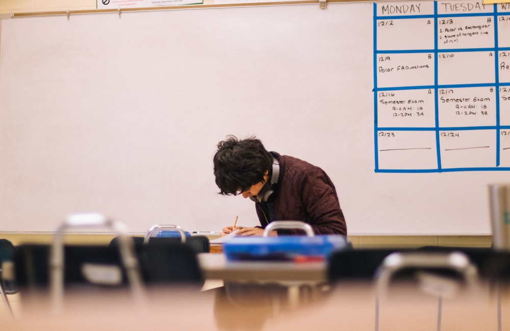 Man in brown sweater sitting on chair and taking an exam.