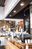 A rustic wooden coffee counter bathed in soft morning light with earth-toned mugs and a vintage espresso machine.