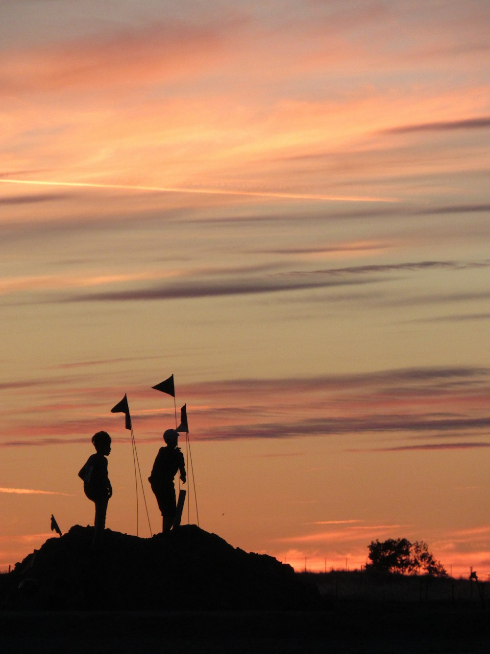 silhouette of 2 person sitting on rock during sunset