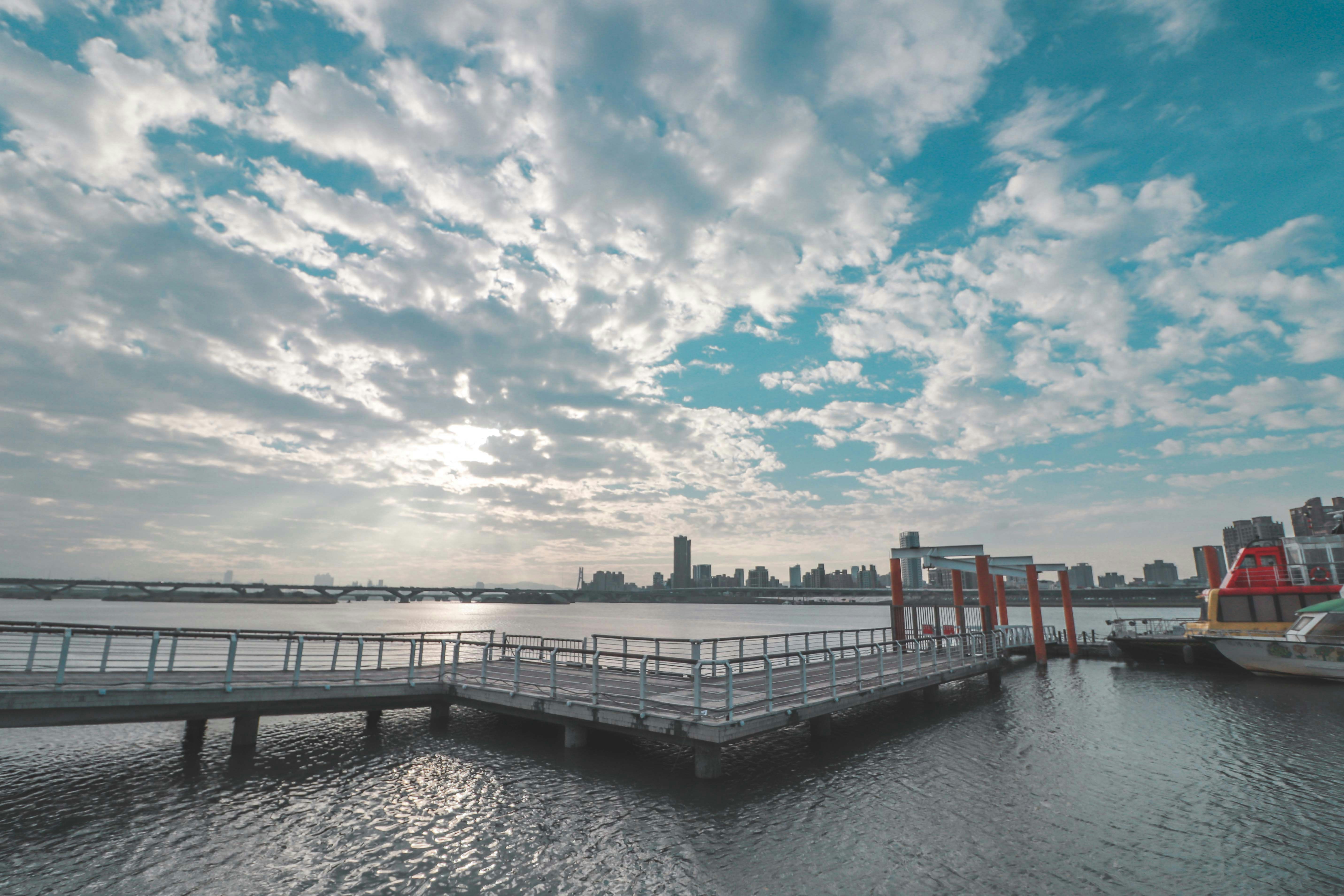 gray wooden dock on body of water under blue and white cloudy sky during daytime