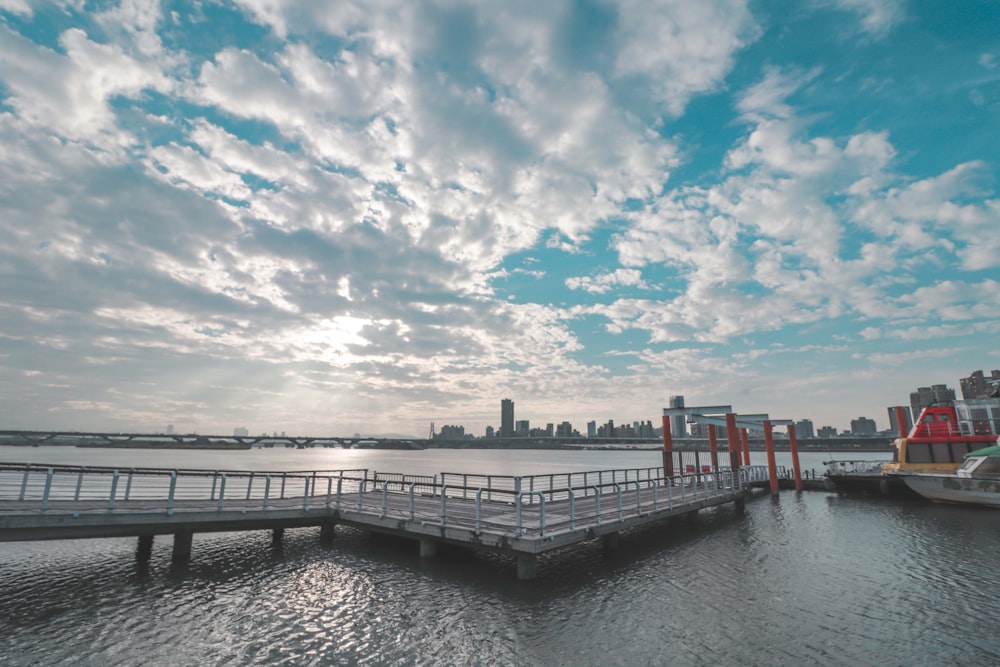 muelle de madera gris en el cuerpo de agua bajo el cielo nublado azul y blanco durante el día