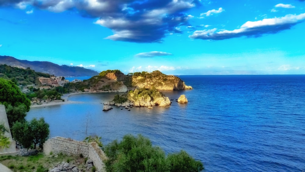 green and brown rock formation on blue sea under blue sky during daytime