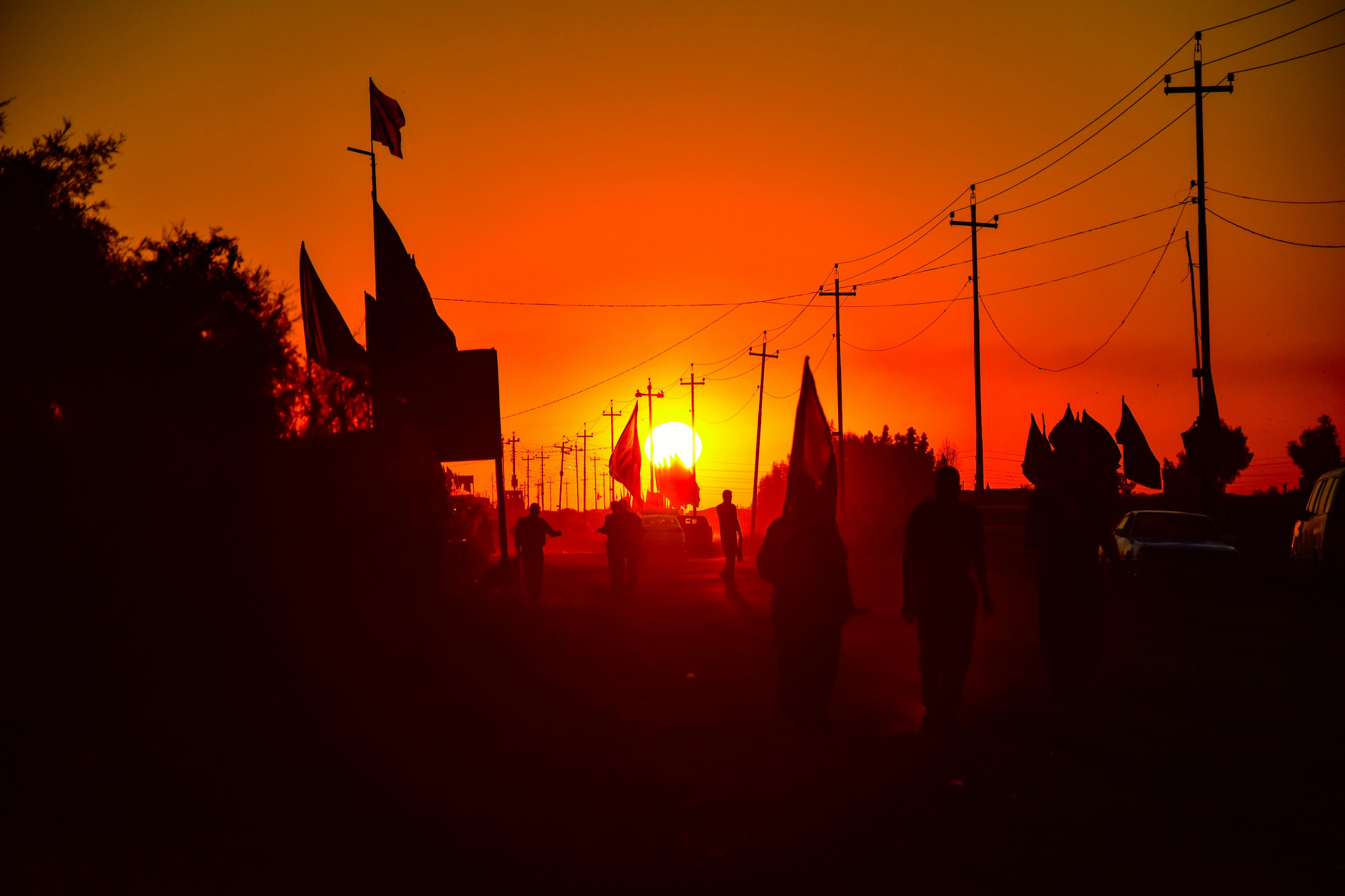 a group of people walking down a street at sunset