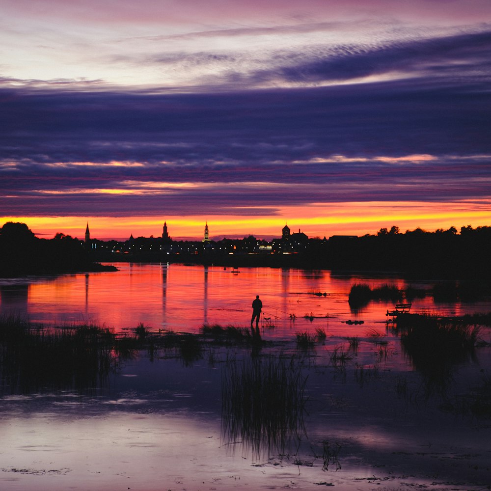 silhouette de personnes sur le lac pendant le coucher du soleil