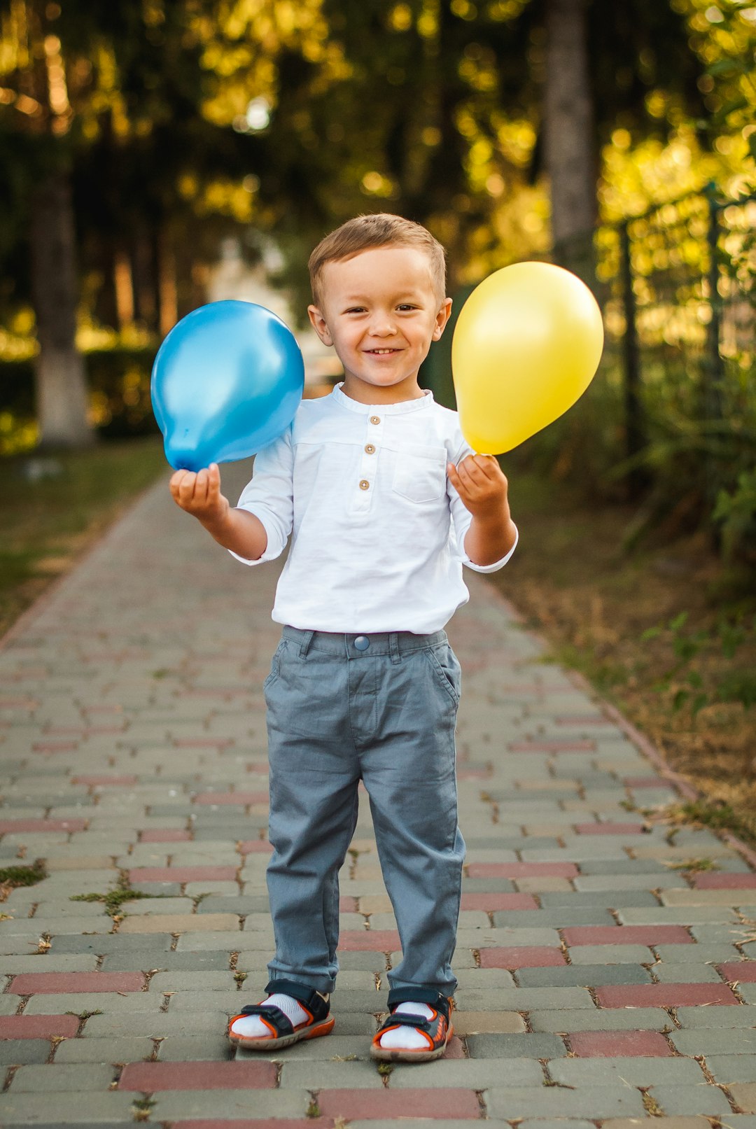 boy in white button up shirt and blue denim jeans holding yellow balloons