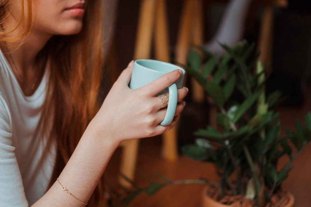 woman holding white ceramic mug