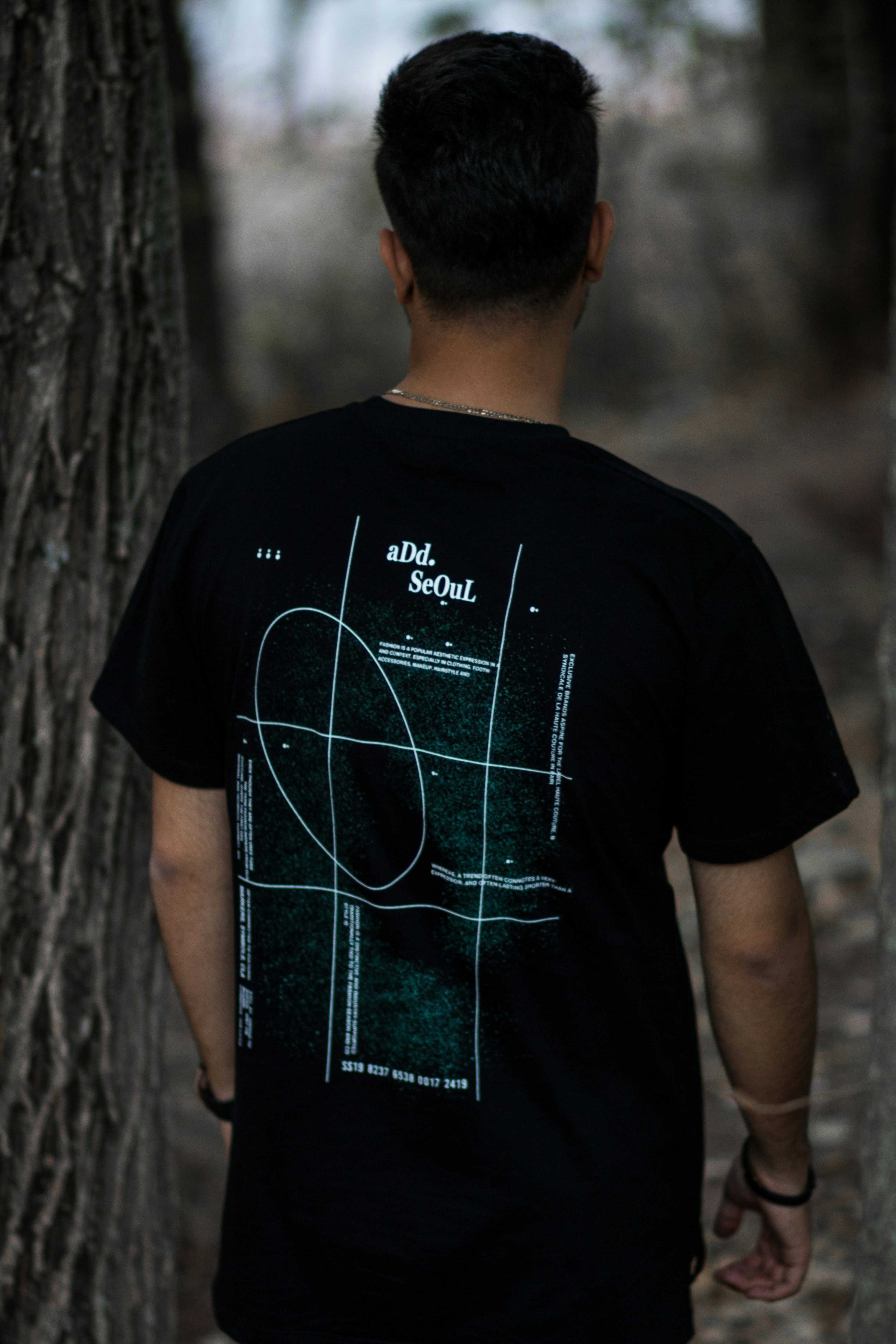 uomo in t-shirt girocollo nera in piedi accanto all'albero