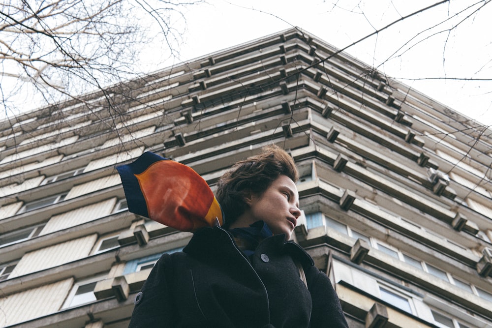 woman in black jacket holding orange umbrella