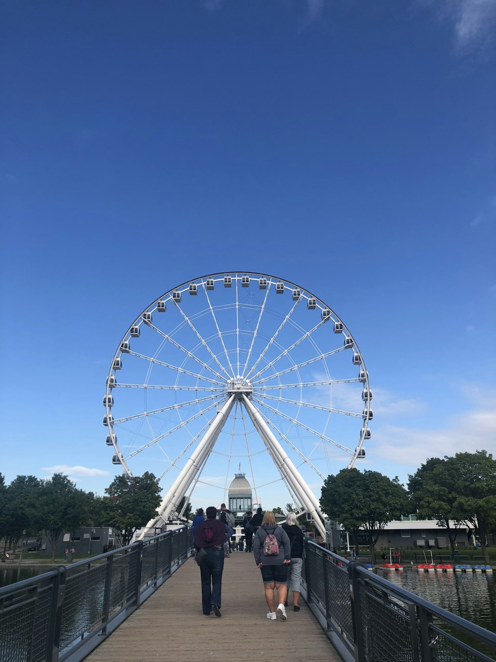 people walking on street near ferris wheel under blue sky during daytime