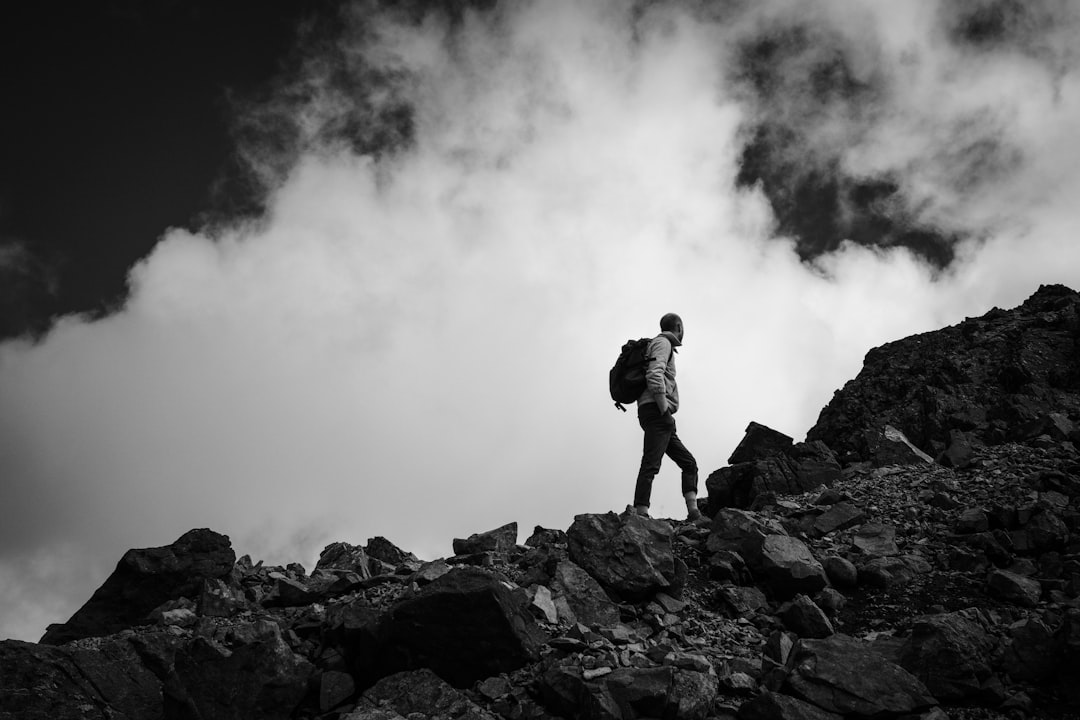 man in black jacket standing on rock formation