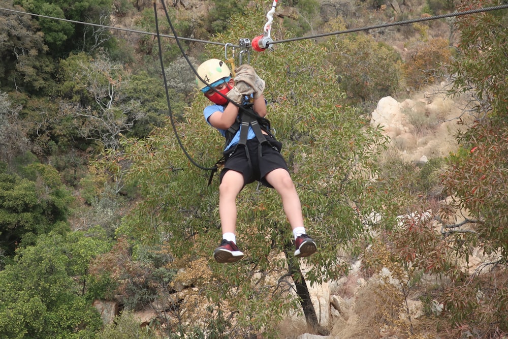 woman in blue shorts and white helmet climbing on mountain during daytime