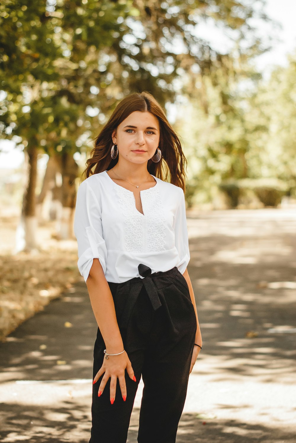 woman in white shirt and black skirt standing on road during daytime