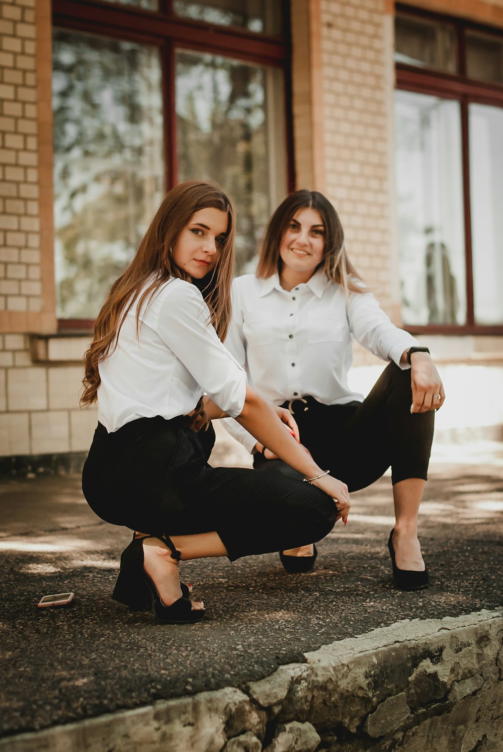 woman in white dress shirt and black skirt sitting on concrete floor