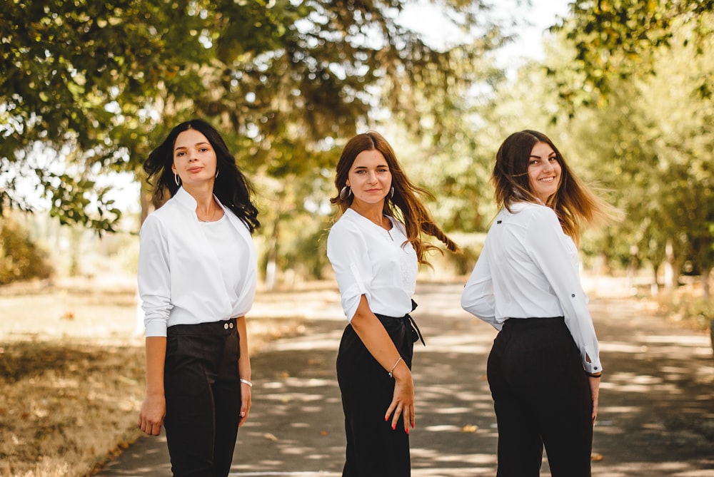 2 women in white dress shirt and black pants standing on brown wooden dock during daytime