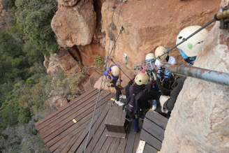 Participants learning rope techniques on a rocky canyon wall under expert guidance.