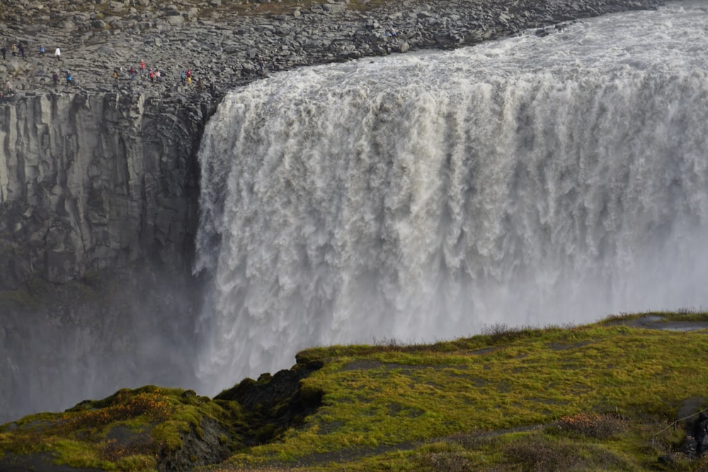 waterfalls on green grass field during daytime