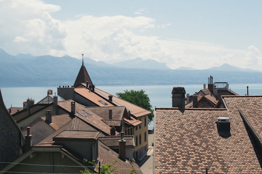 brown concrete houses near sea under blue sky during daytime in Lavaux Switzerland