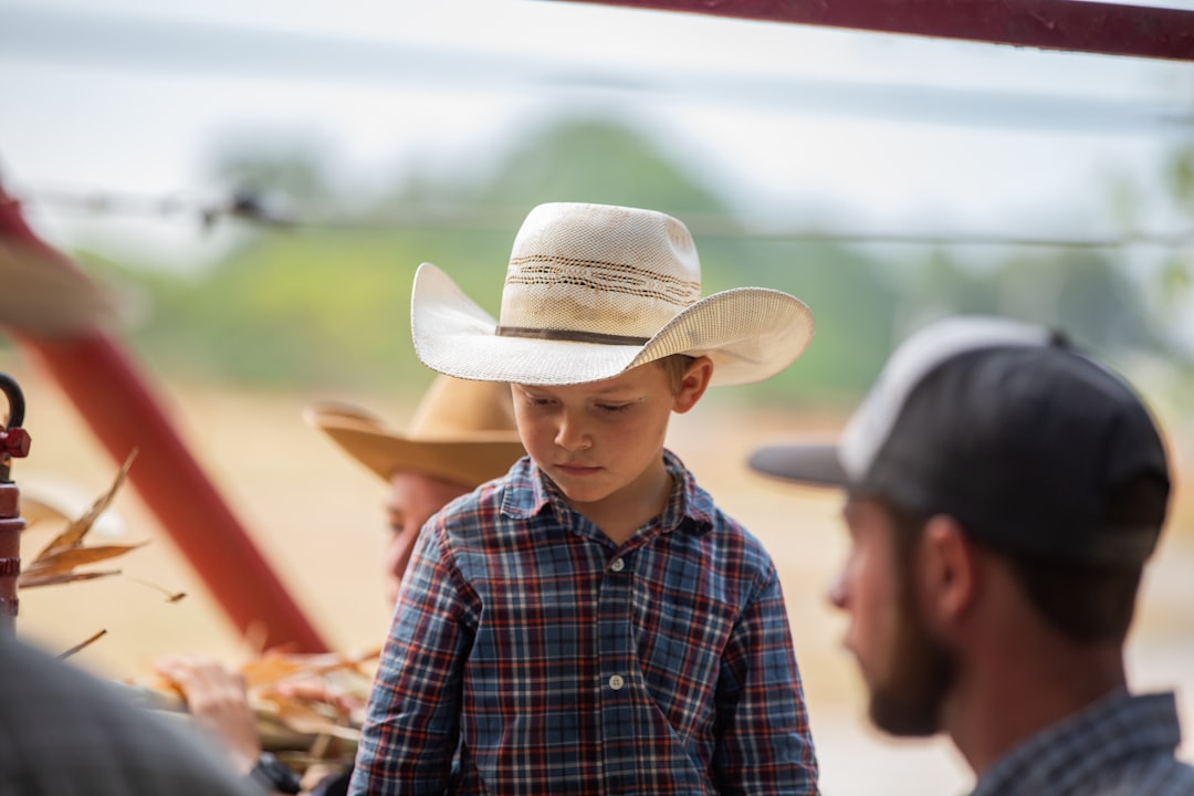 boy in blue white and black plaid dress shirt wearing white cowboy hat