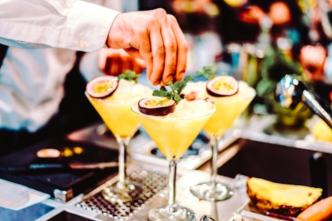 person holding clear cocktail glass with yellow liquid