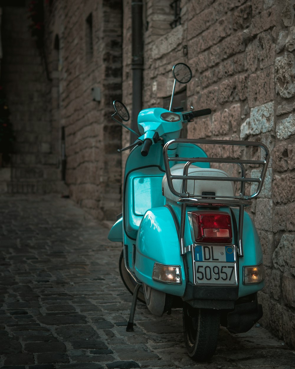 Scooter rojo y azul estacionado junto a una pared de ladrillos marrones