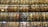 An expansive multi-level library wall filled with countless books arranged neatly on shelves. The shelves are illuminated evenly, creating a warm and inviting atmosphere. The variety of book spines display a range of colors, sizes, and materials.