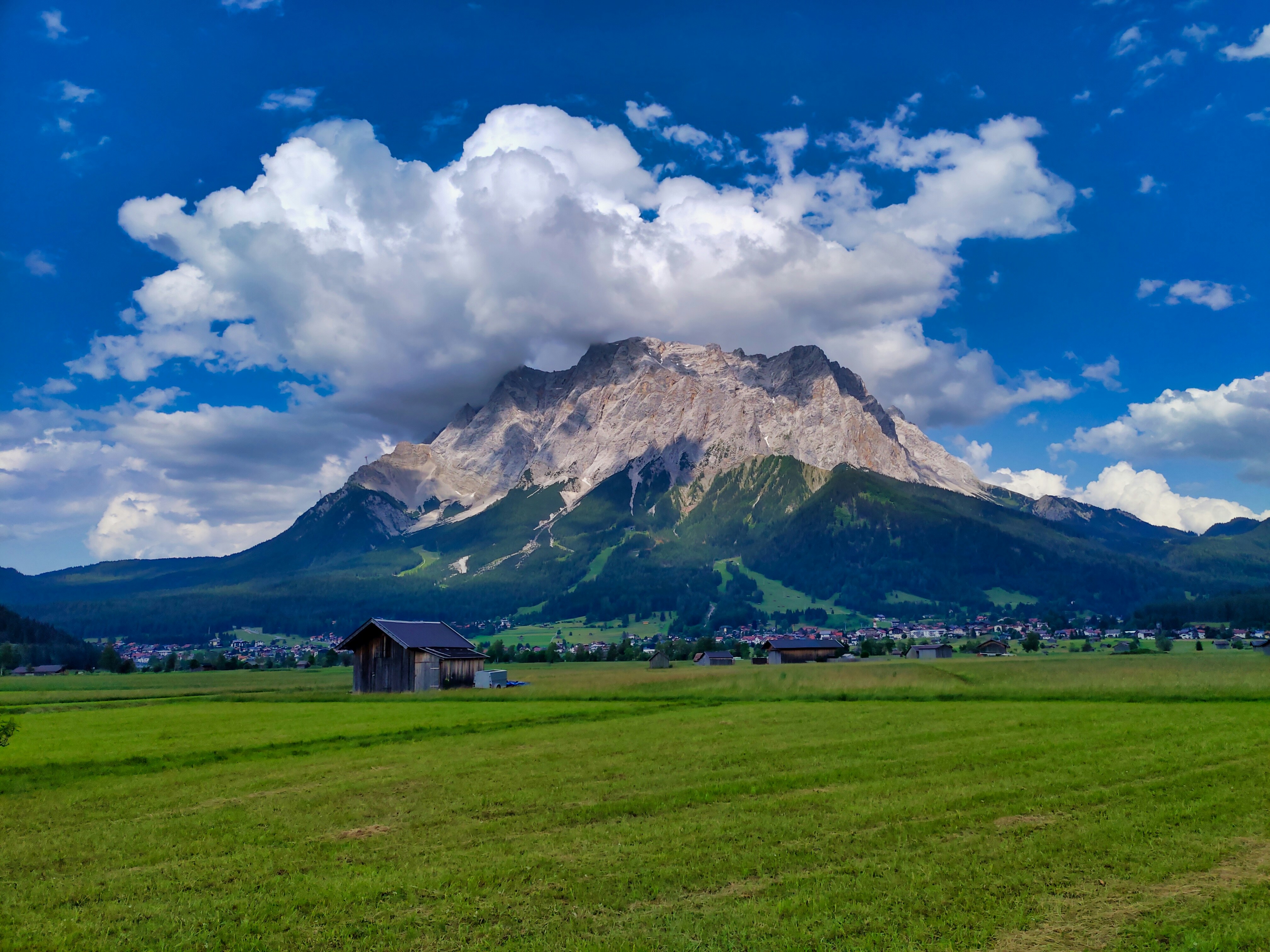 Brown wooden house on green grass field near mountain under white ...