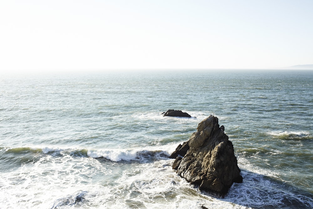 ocean waves crashing on black rock formation during daytime