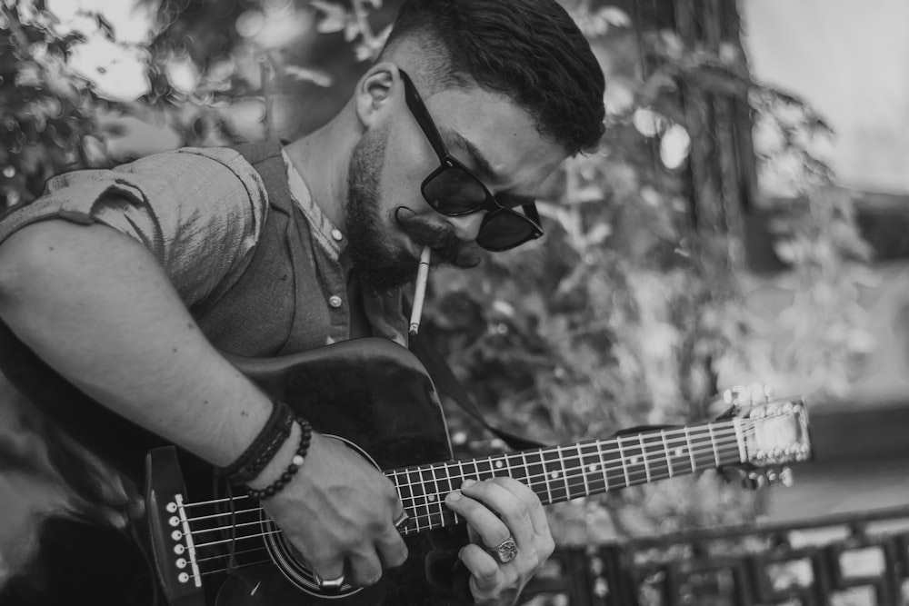 man playing acoustic guitar in grayscale photography