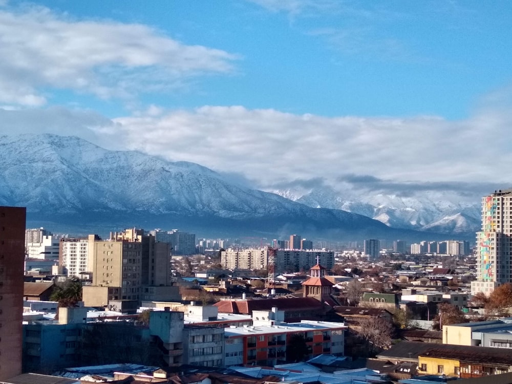 city with high rise buildings near mountain under white clouds during daytime