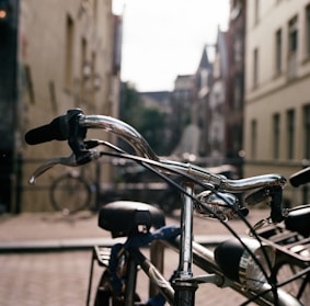 Close-up of sleek bike handlebars with leather grips against a blurred urban background
