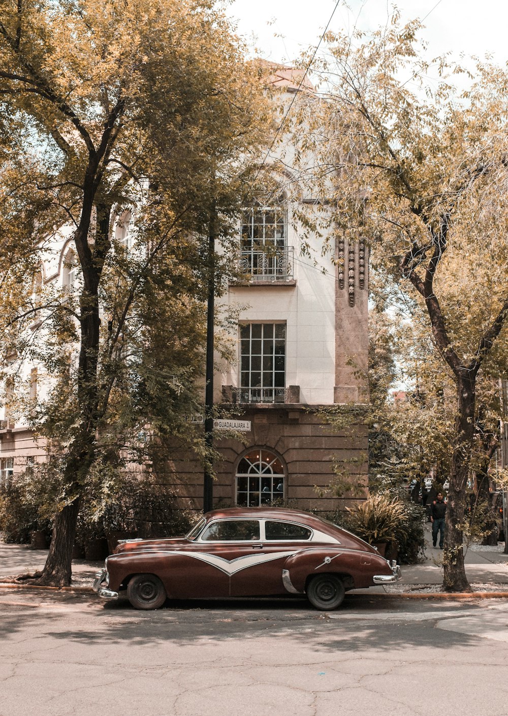 cupê vermelho estacionado ao lado do edifício de concreto marrom durante o dia