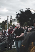 The senator addressing a crowd during a public forum under a bright sky.