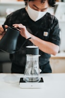 person pouring water on black ceramic mug