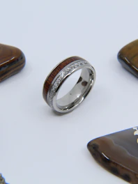 Close-up of a silver ring with a natural gemstone, resting on a rustic wooden table in a sunny boutique.
