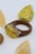 A wooden ring featuring a resin component with yellow and brown inclusions lies amid several polished stones, predominantly yellow and brown in color.